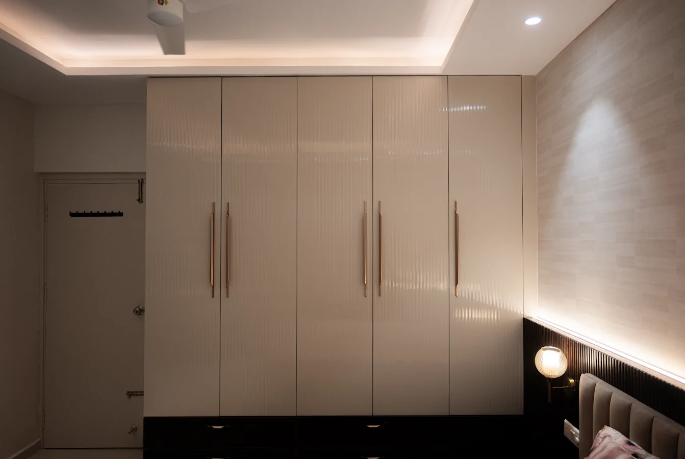 Executed bedroom wardrobe with integrated handles and warm indirect lighting