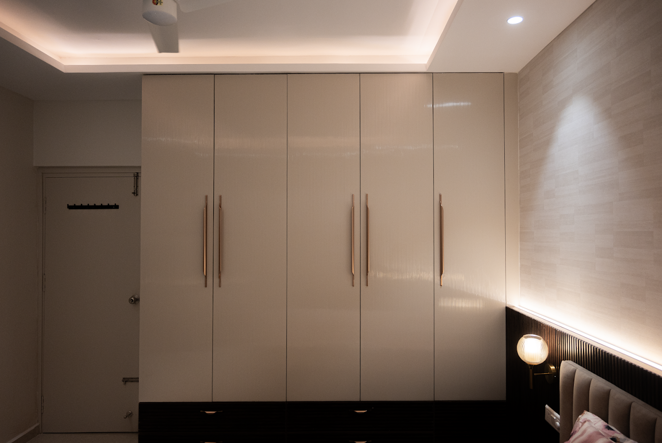 Executed bedroom wardrobe with integrated handles and warm indirect lighting